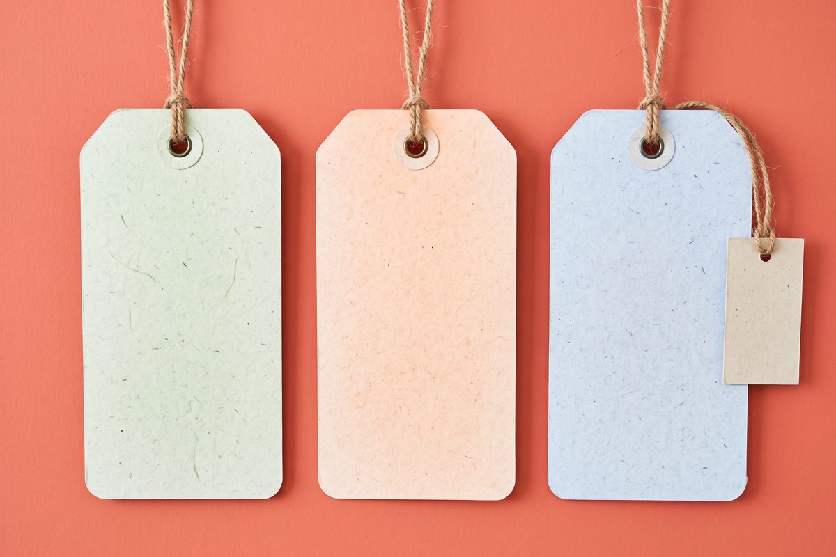 Three large blank price tags in green, orange and blue with one small extra tag, coral background