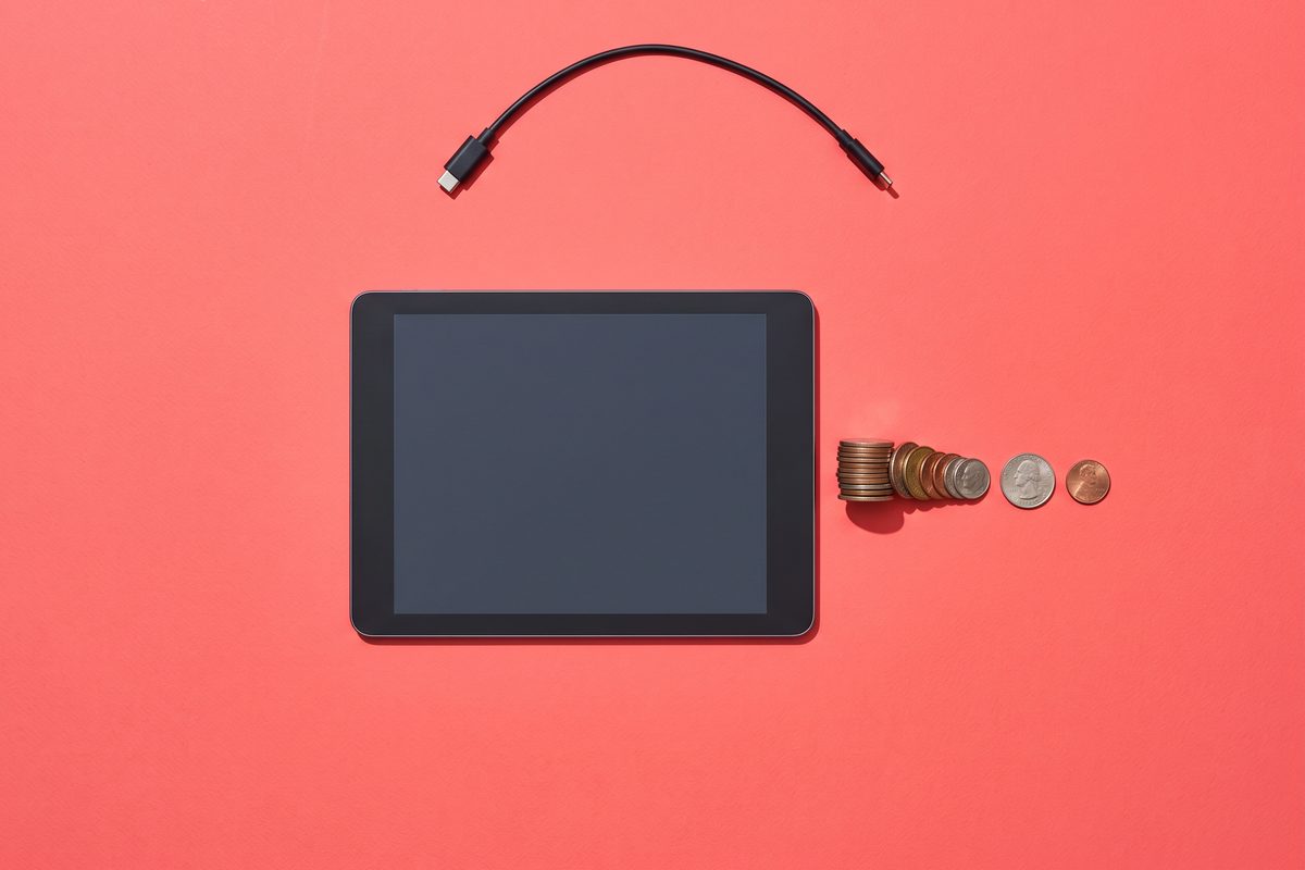 Closed tablet on a coral background beside a row of coins that thins to nothing and an unplugged cable