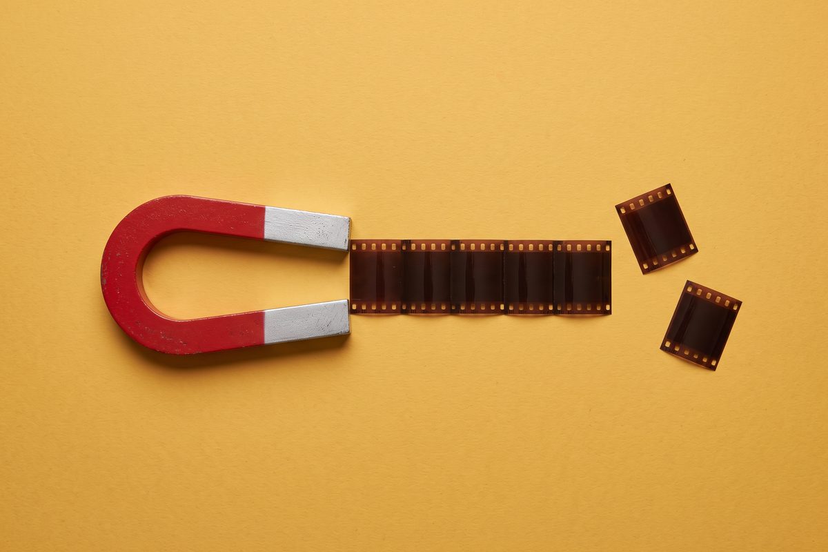 A large horseshoe magnet pulling small film-strip pieces into a single gapless row